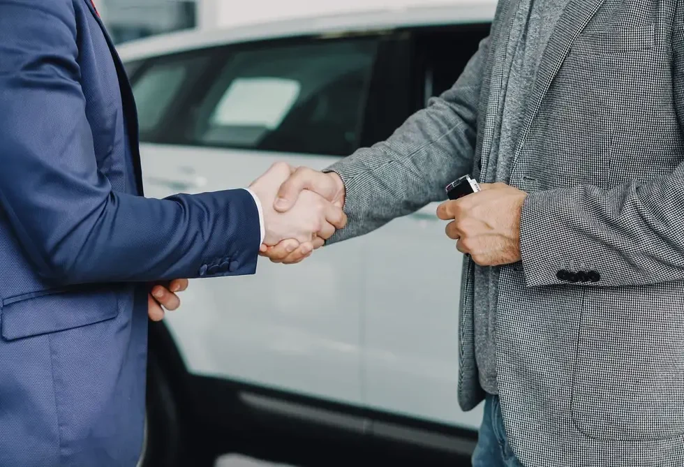 Two businessmen shaking hands in a car dealership, sealing a deal