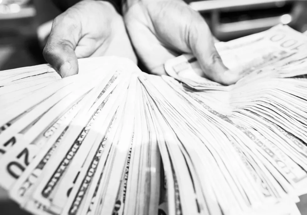 Close-up of hands holding a large amount of cash in black and white