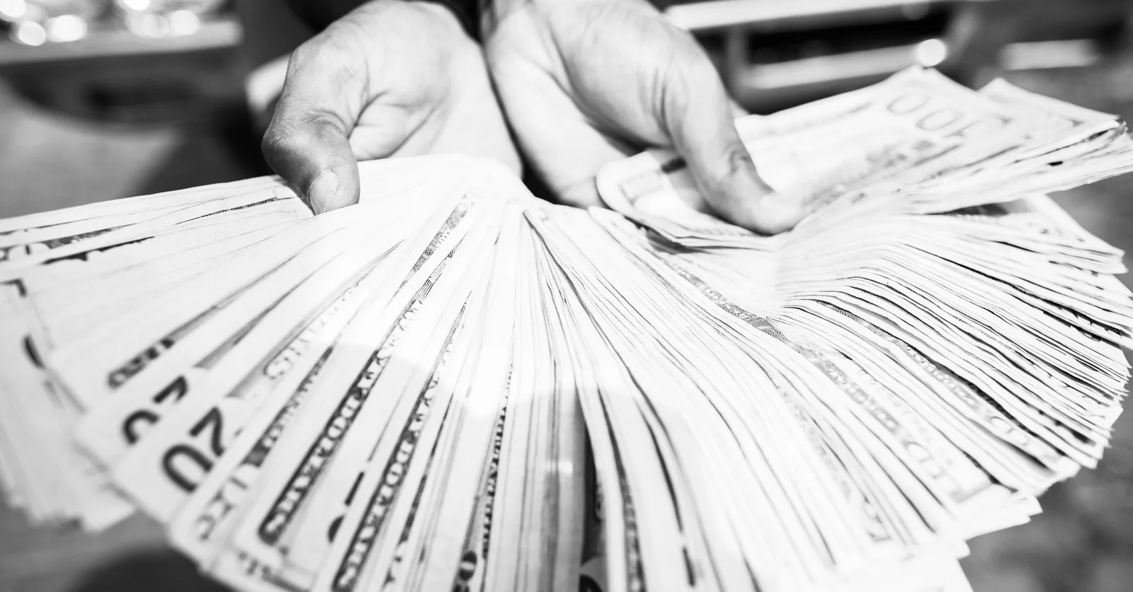 Close-up of hands holding a large amount of cash in black and white